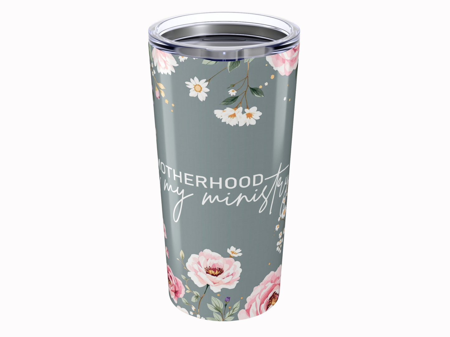 A floral tumbler with pink and white flowers on a grey background. Text reads "Motherhood is my ministry" in stylish script, conveying warmth.