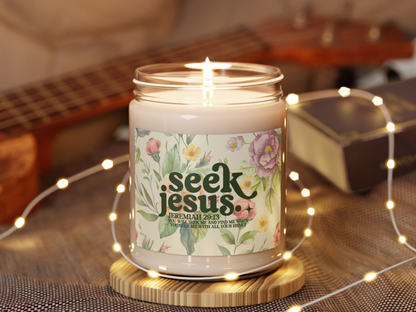 Lit candle with "Seek Jesus" label featuring colorful flowers and a Bible verse. Warm ambiance with soft string lights and a blurred ukulele.