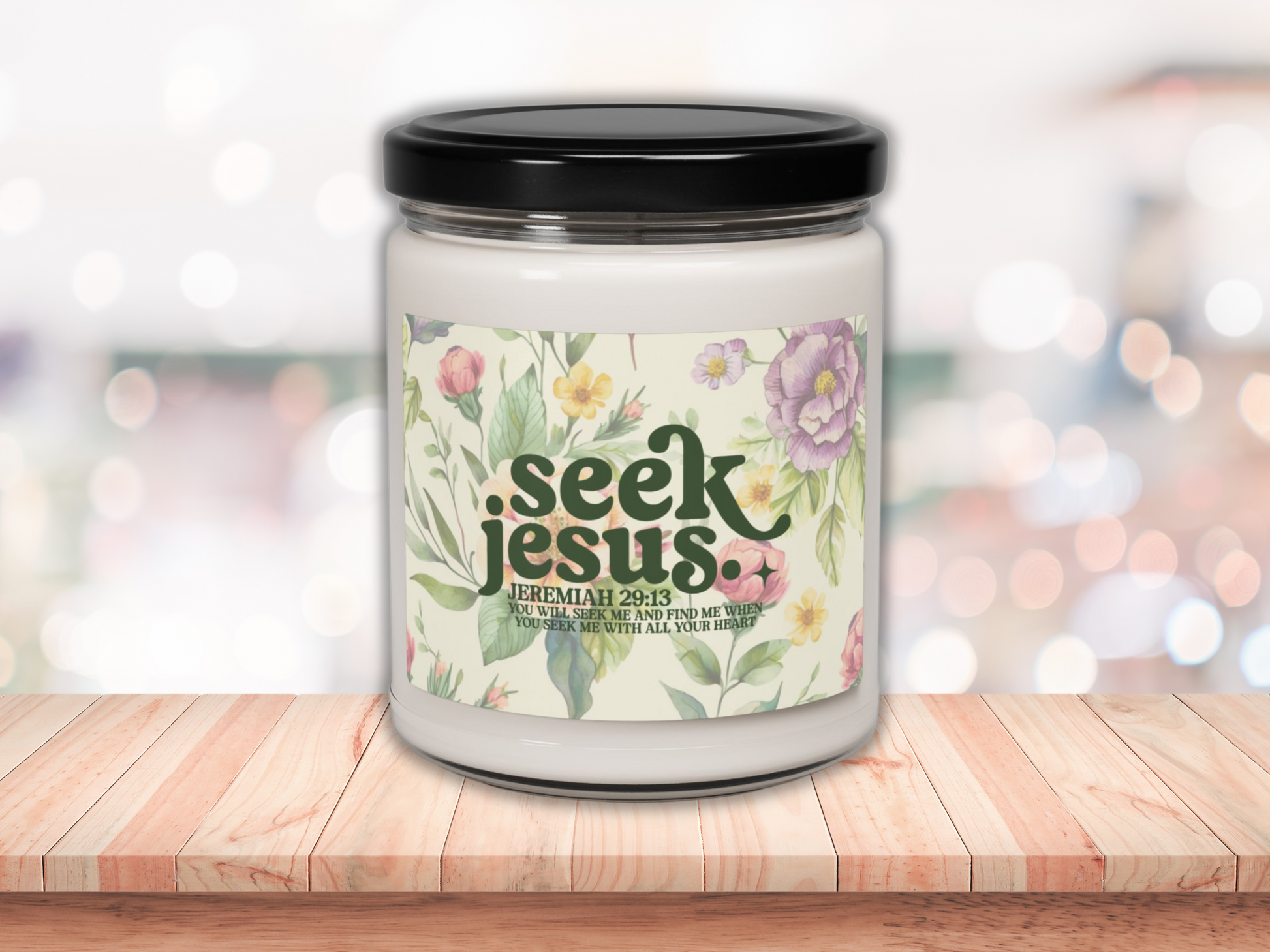 A soy candle with bible verse with a black lid on a wooden surface. The label reads "Seek Jesus" with floral designs, conveying peace and spirituality.