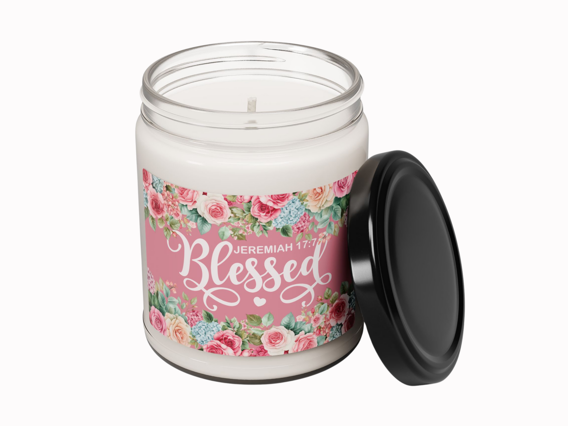 Glass jar candle with black lid, pink label featuring floral design and "Jeremiah 17:7 Blessed" text. Warm, serene, decorative vibe.
