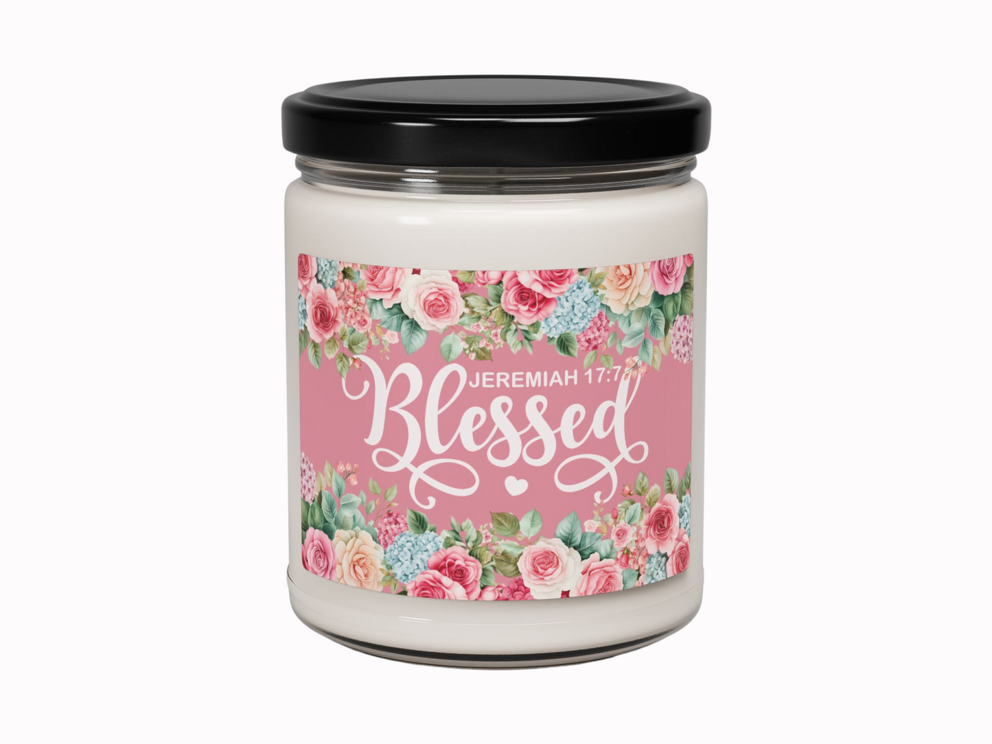 Glass jar candle with a black lid, featuring a floral label design. The pink label reads "Blessed" with "Jeremiah 17:7" in white script.