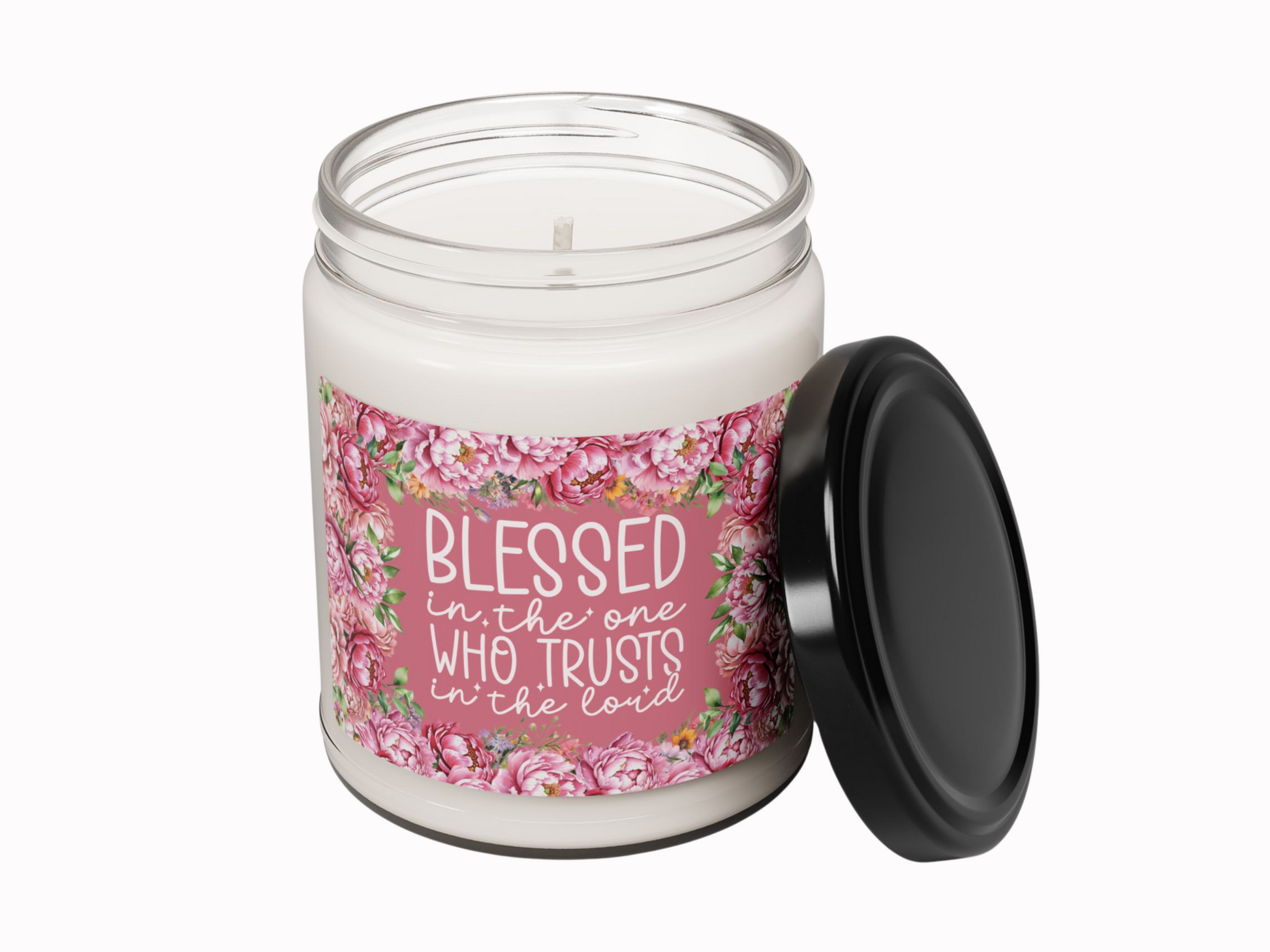 White candle in a glass jar with a floral label. Text reads, "Blessed is the one who trusts in the Lord." Black lid placed beside the jar.