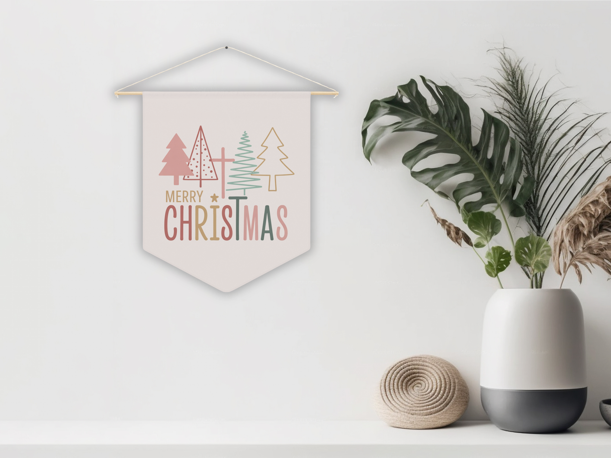 Decorative Christmas pennant flag with trees and 'Merry Christmas' text, placed on a white surface with plants and a vase.