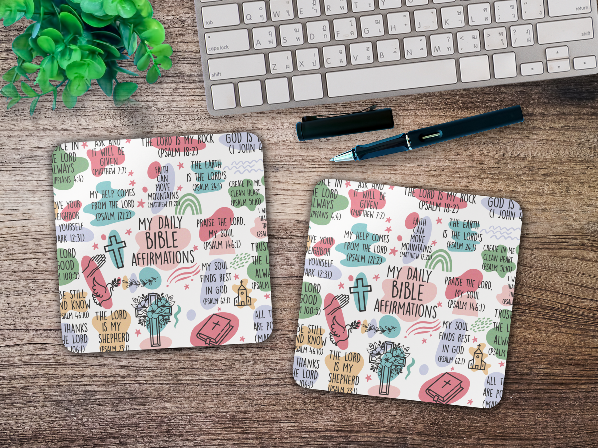 Two Bible verse affirmation coasters styled on a wooden desk beside keyboard, pen, and plant for a faith-inspired workspace.