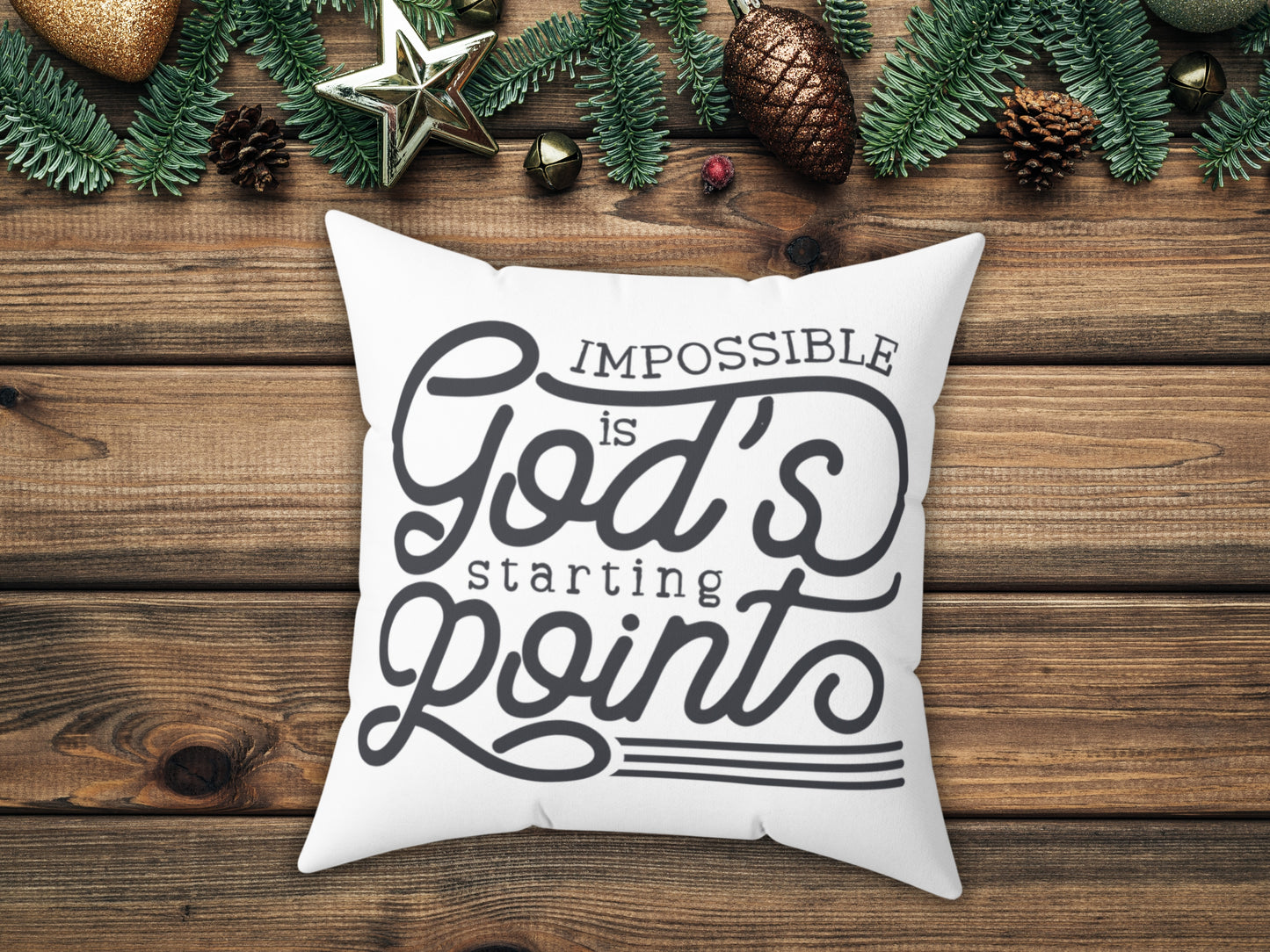 White pillow with motivational quote on a wooden surface with Christmas decorations