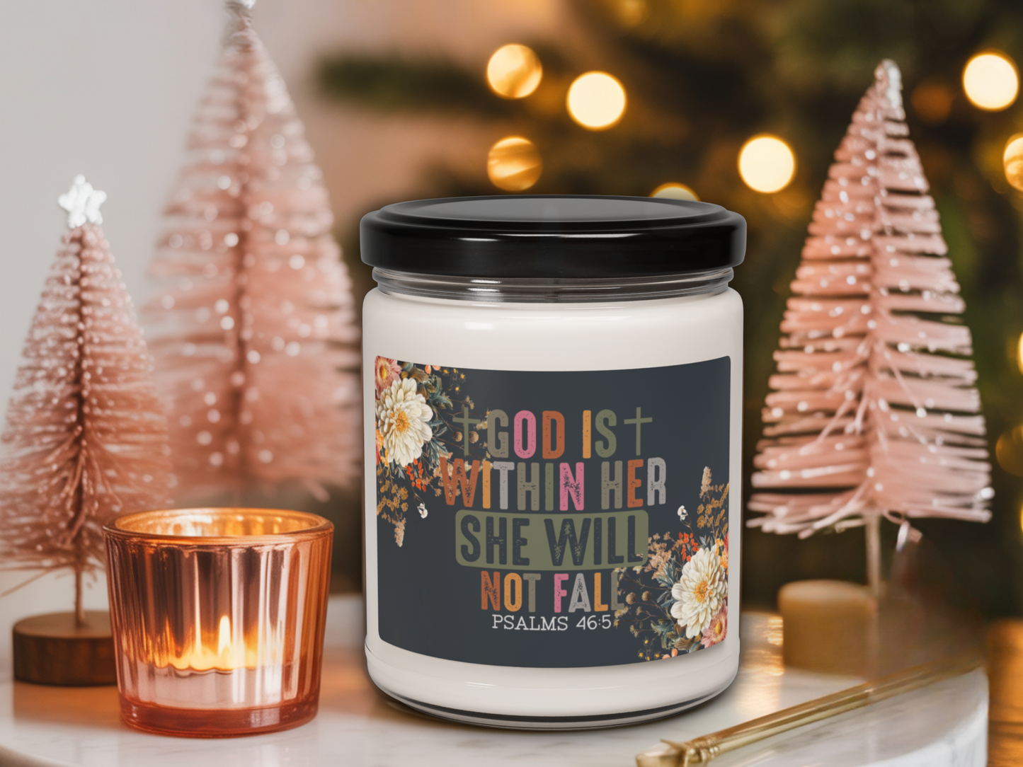 Candle jar with motivational label in a festive setting with Christmas trees and lights.