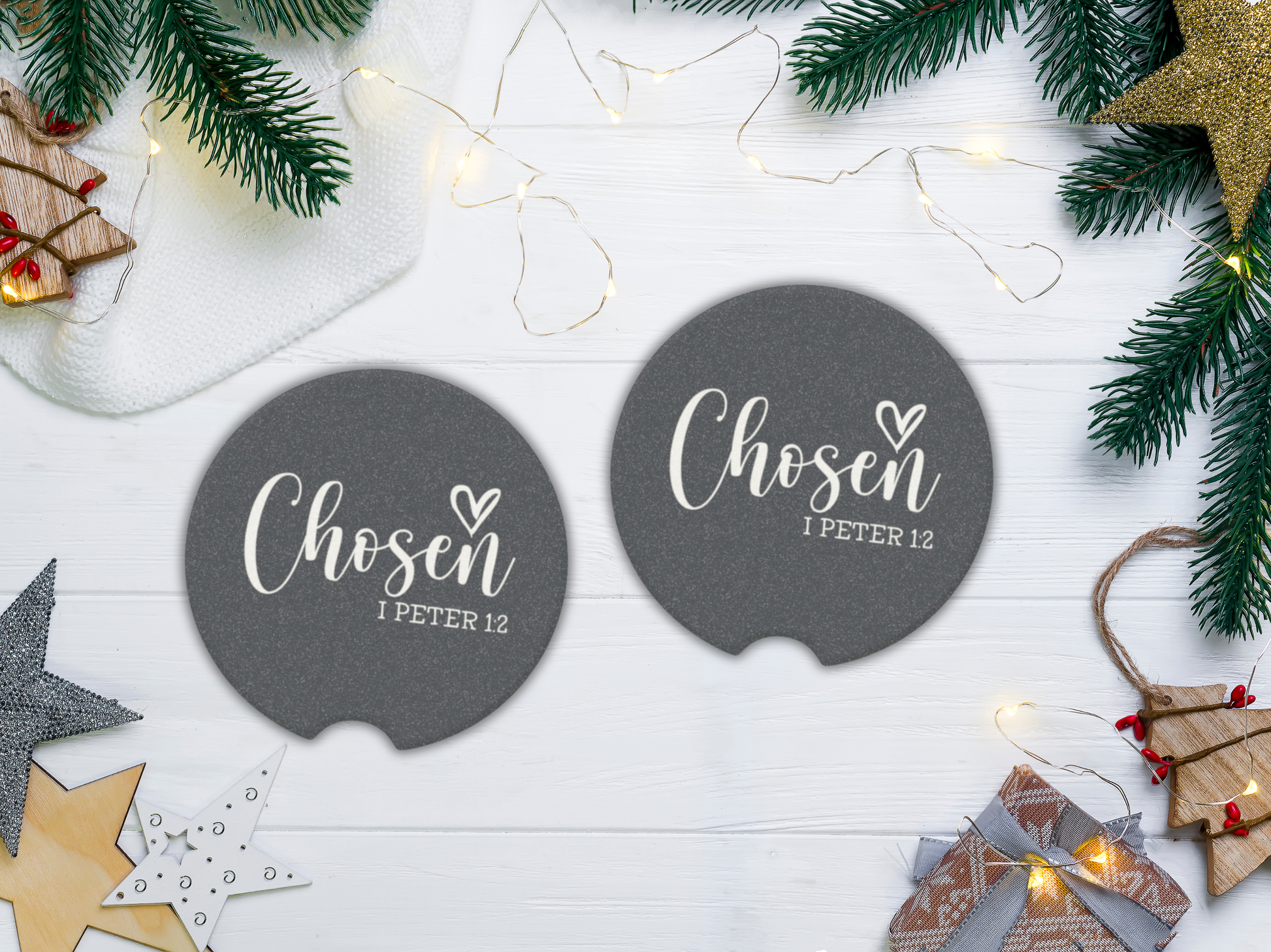 Two navy coasters with 'Chosen I Peter 1:2' text on a white wooden surface with Christmas decorations.