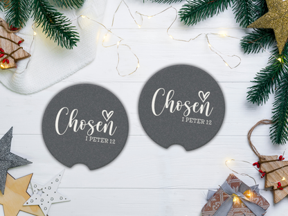 Two navy coasters with 'Chosen I Peter 1:2' text on a white wooden surface with Christmas decorations.
