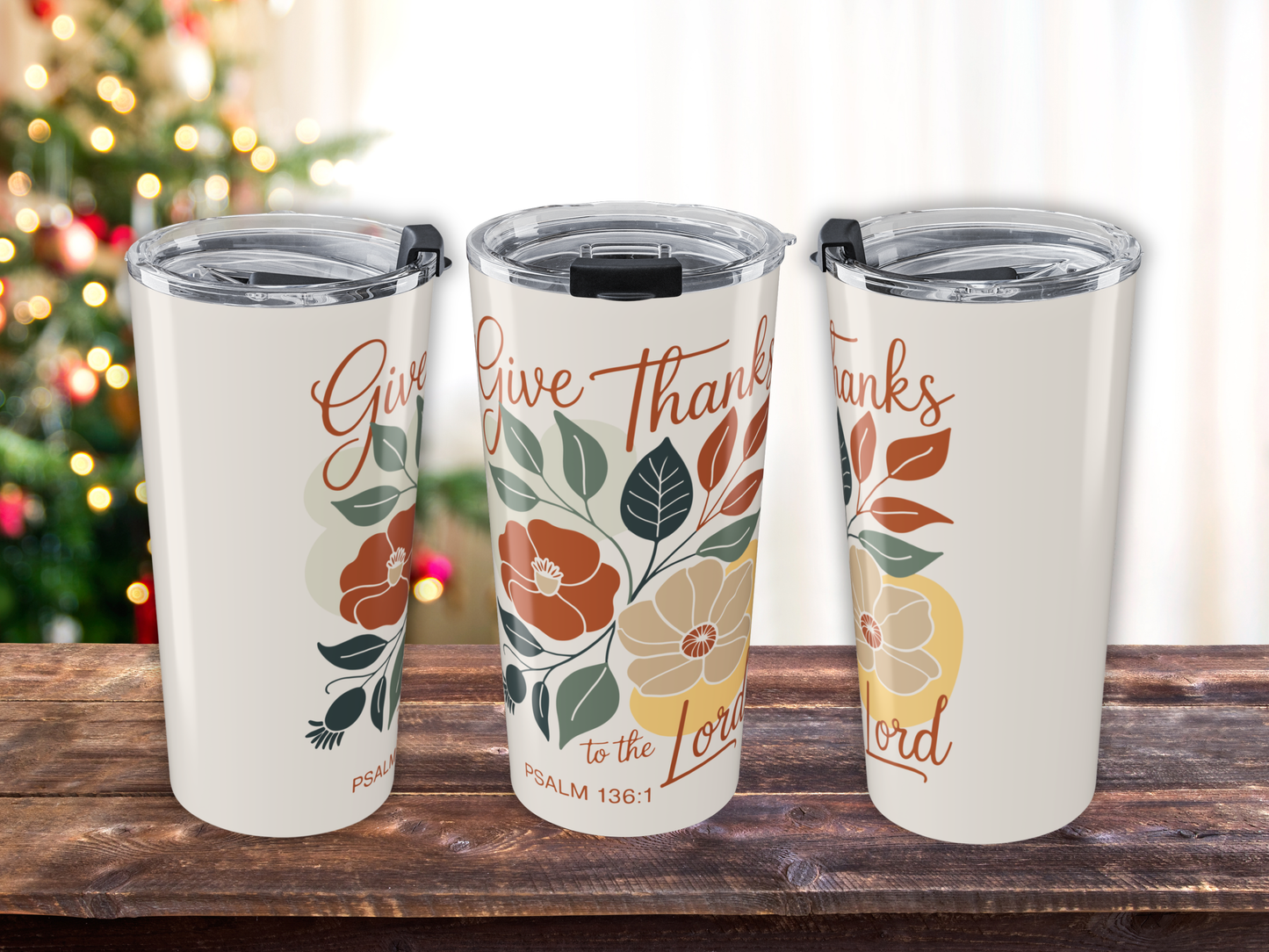 Three insulated tumblers with floral designs and text on a wooden surface.