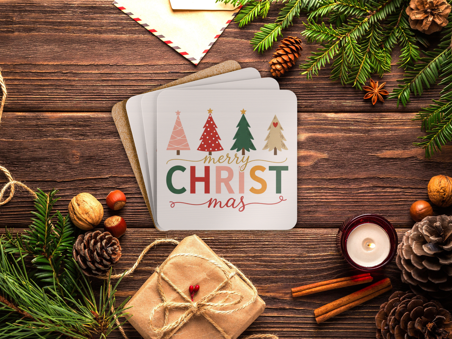 Christmas card with trees and 'Merry Christmas' text on a wooden surface with festive decorations.