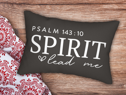 Decorative pillow with 'Psalm 143:10 Spirit lead me' text on a wooden surface with a red and white patterned fabric.