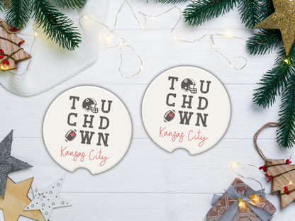 Two 'Touchdown Kansas City' coasters on a festive background with Christmas decorations.