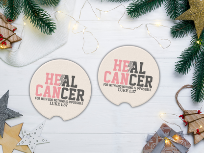 Two coasters with 'HEAL CANCER' text on a white surface with Christmas decorations.