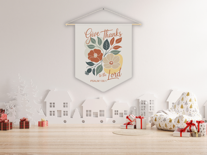 Decorative wall pennant with floral design and text on a white wall with Christmas decorations.