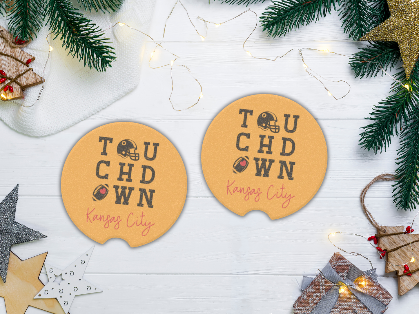 Two round yellow coasters with 'Touchdown Kansas City' text on a white surface with Christmas decorations.