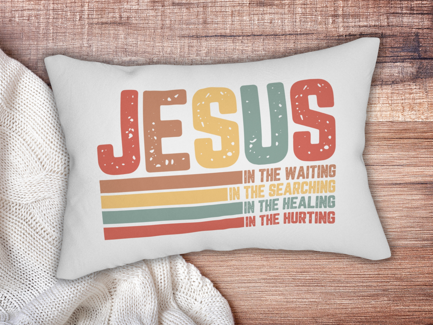 Pillow on a wooden surface styled with a chunky white knit blanket.