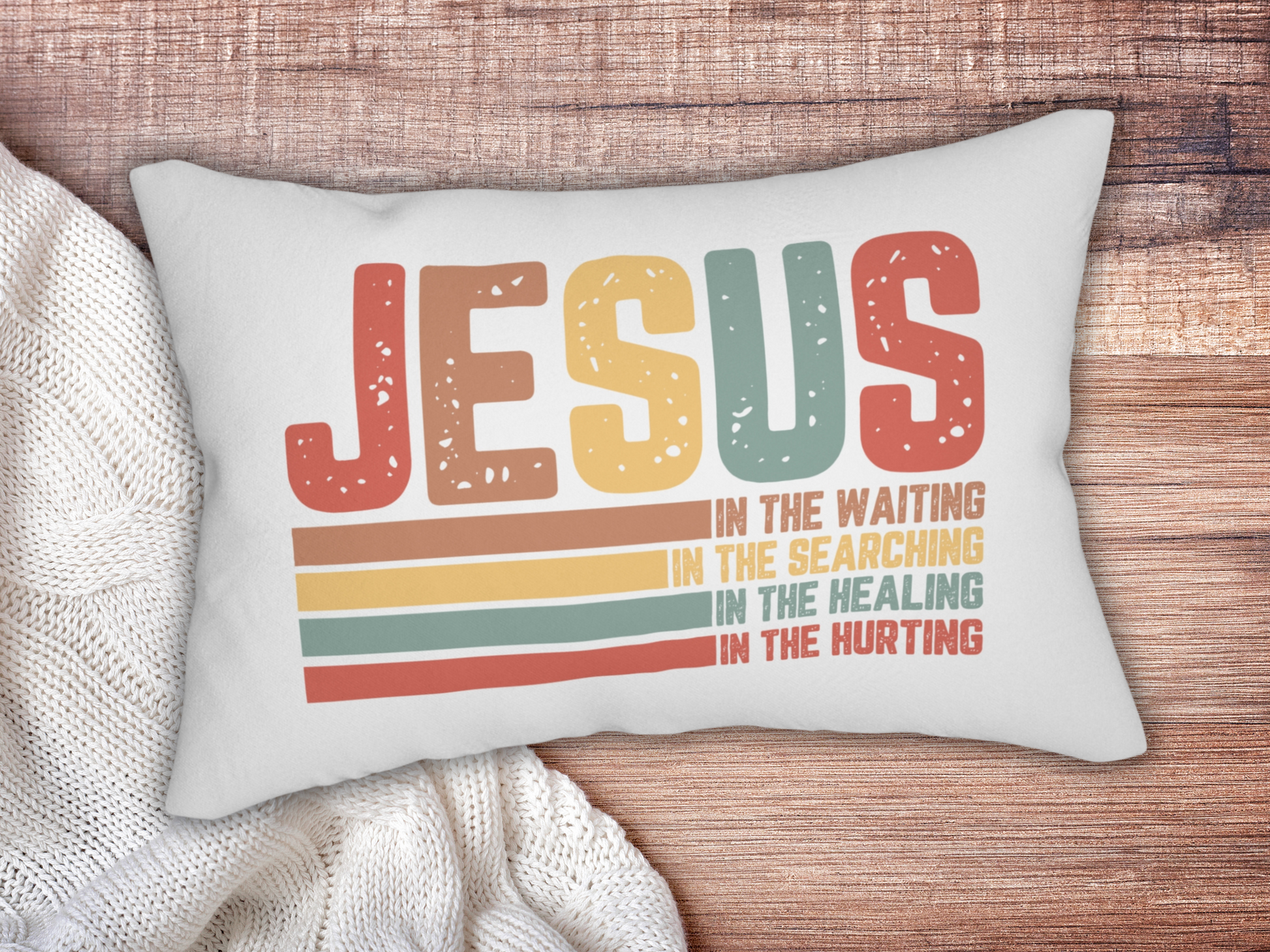 Pillow on a wooden surface styled with a chunky white knit blanket.