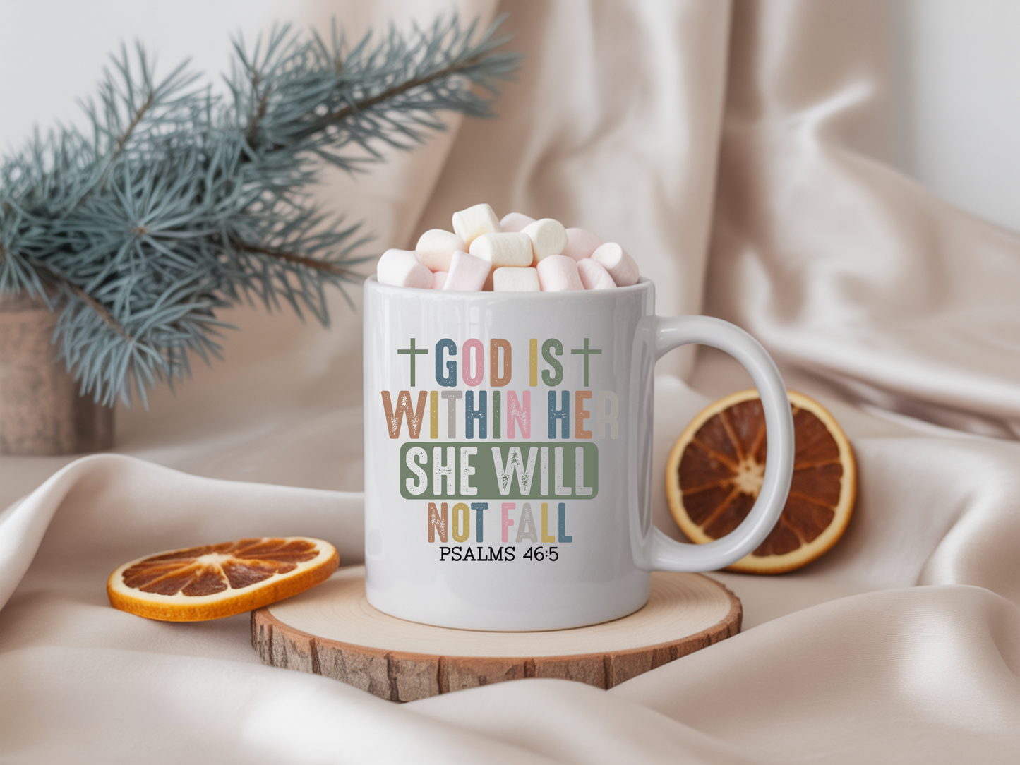 White mug with motivational quote, filled with hot chocolate and marshmallows, on a wooden coaster with decorative elements.