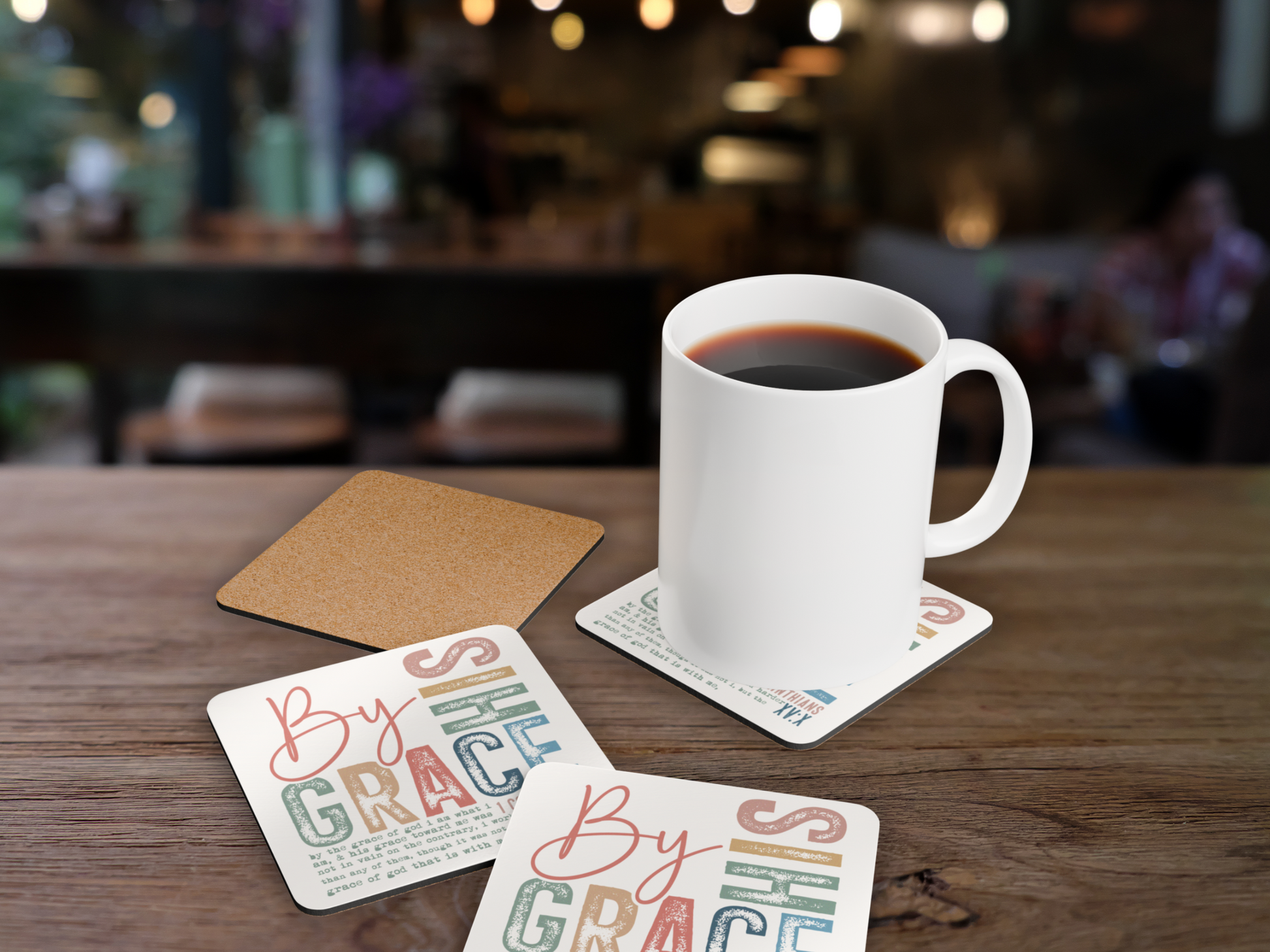 Christian “By His Grace” coaster set with coffee mug, cork backing, and café-style blurred background.