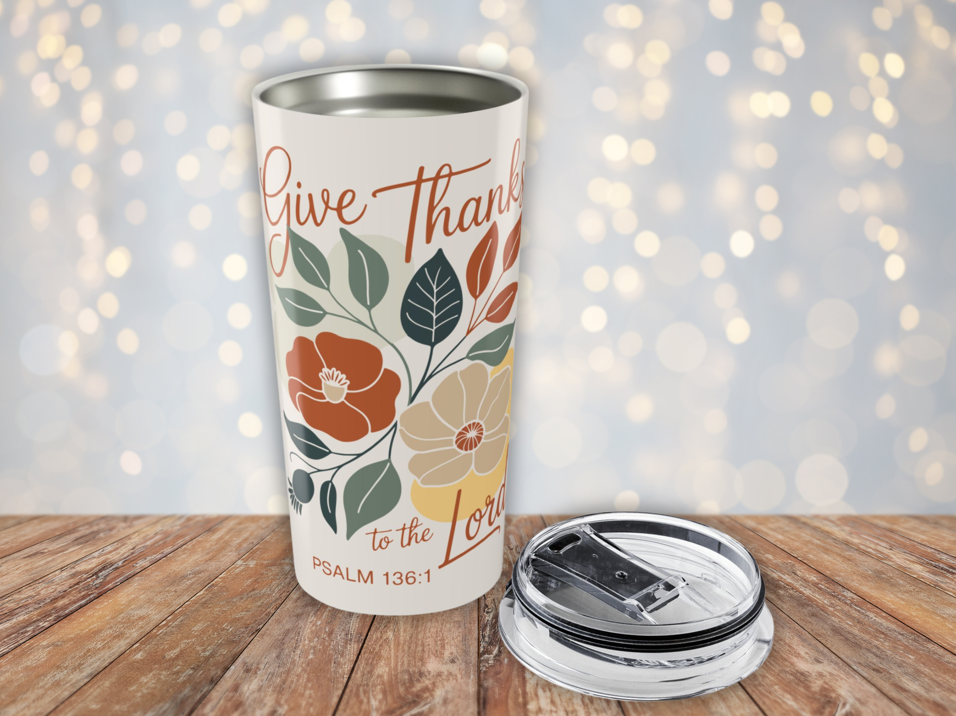 Tumbler with floral design and text on a wooden surface with a blurred light background