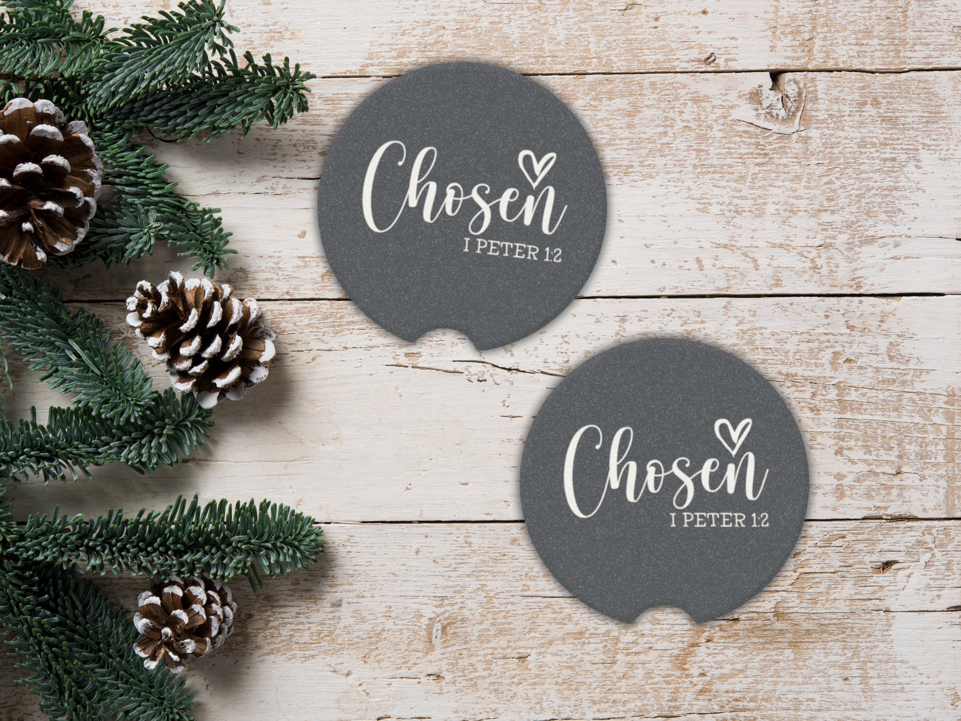 Two navy coasters with 'Chosen 1 Peter 1:2' text on a wooden surface with pinecones and greenery.