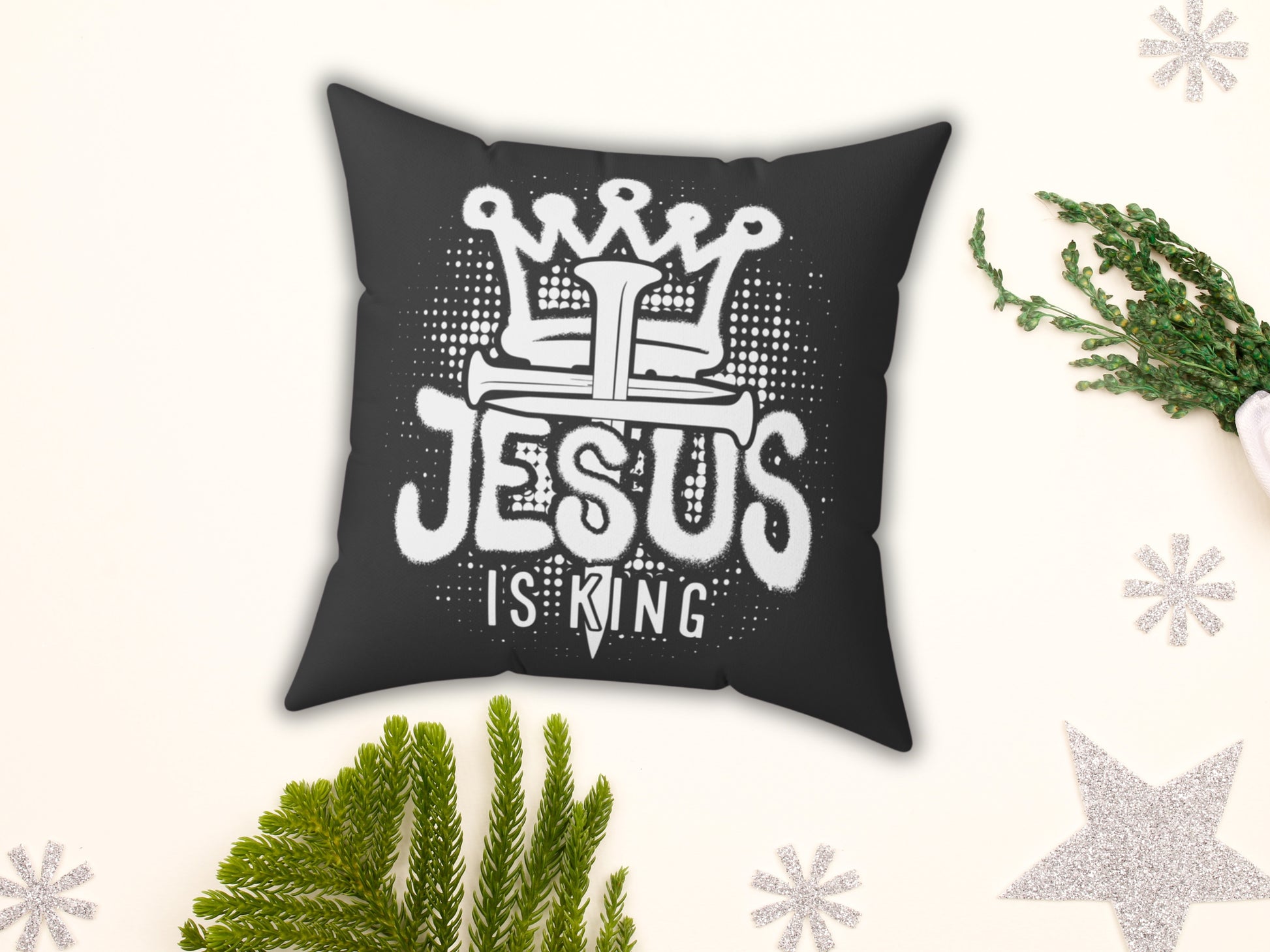 Black pillow with 'Jesus is King' text on a decorative background with greenery and stars.