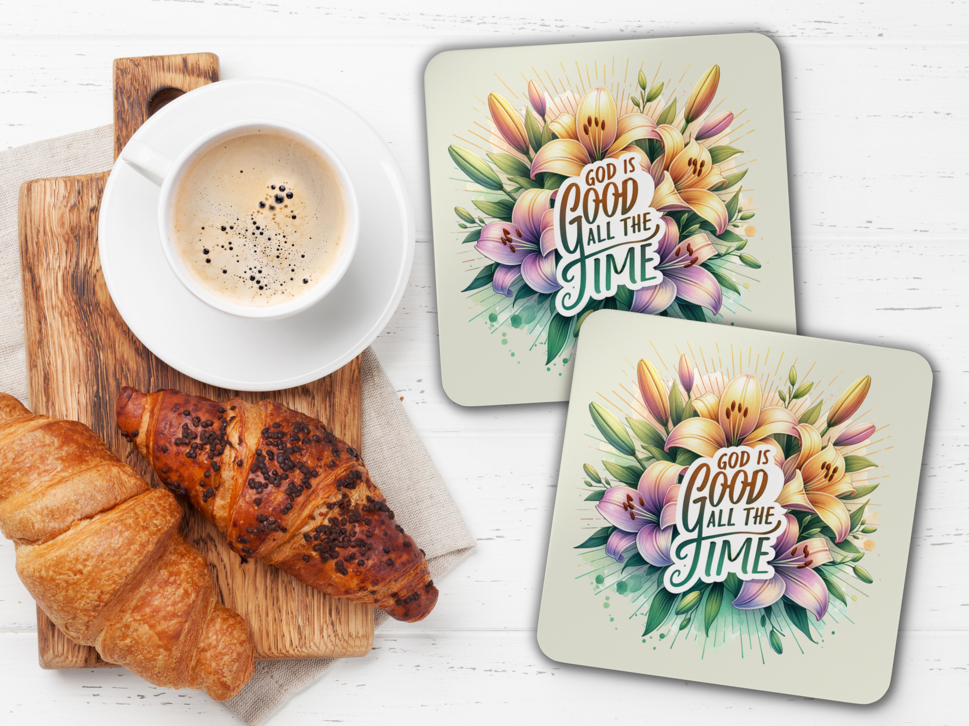 Two floral scripture coasters styled with coffee, croissants, and wooden serving board on a bright white table.