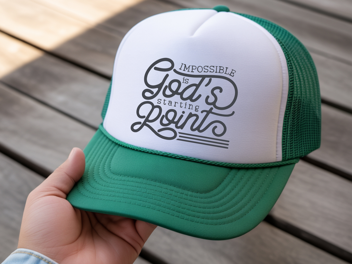 Green and white cap with motivational quote held by a hand on wooden surface
