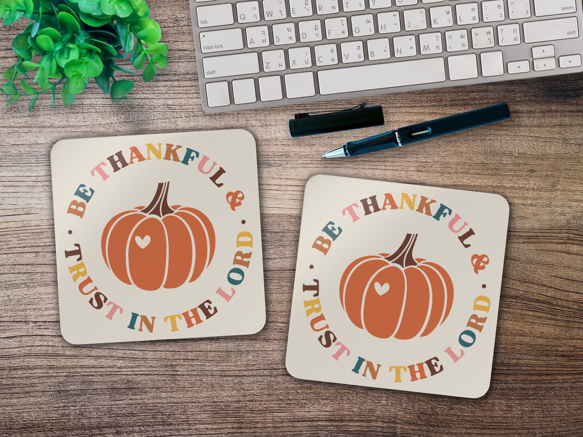 Two “Be Thankful & Trust in the Lord” coasters styled on wooden desk with keyboard, pen, and plant.
