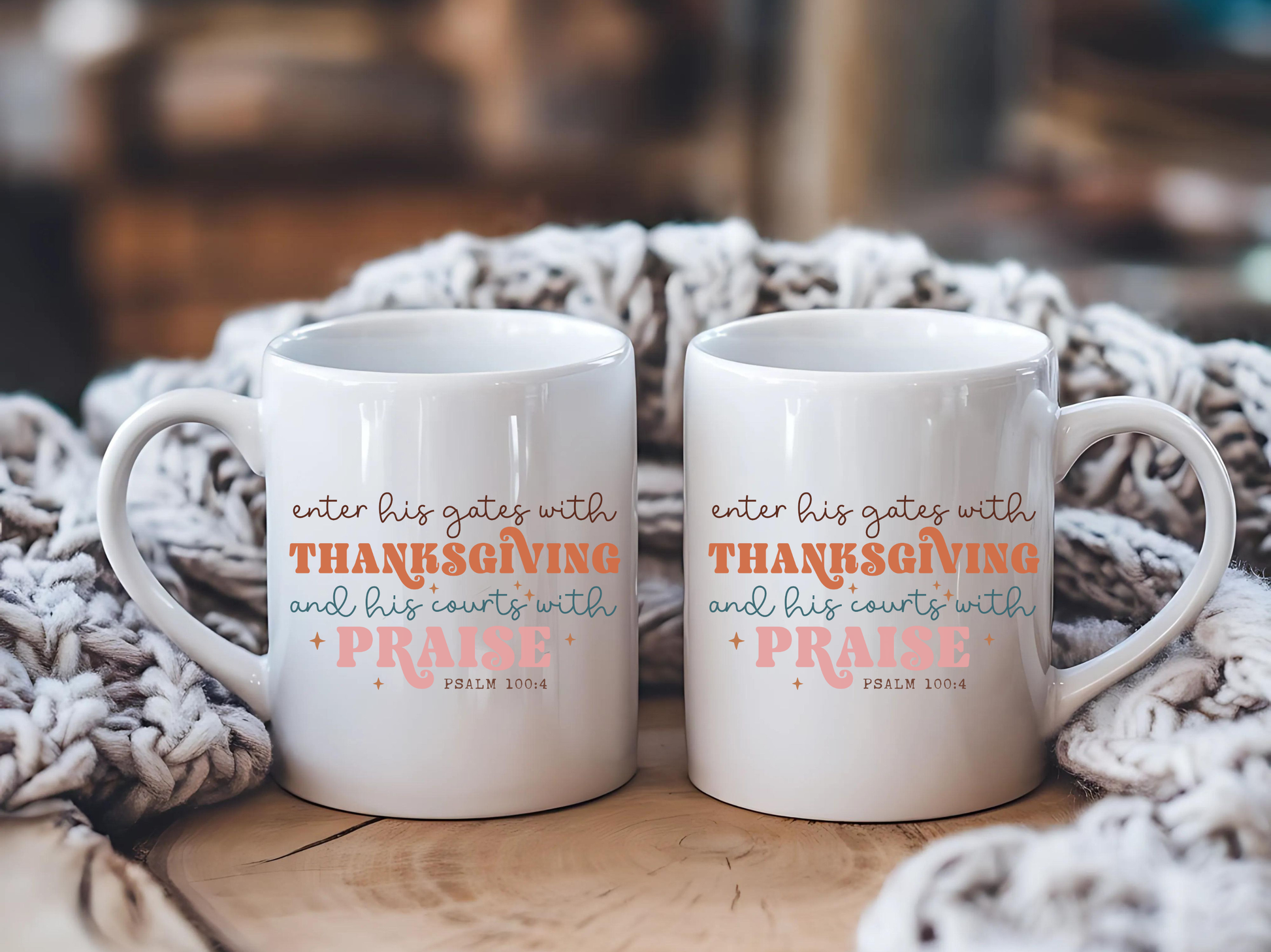 Two white mugs with inspirational text on a wooden surface with a textured blanket in the background.