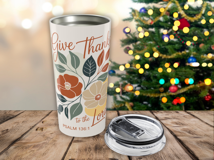 Tumbler with 'Give Thanks to the Lord' text and floral design in front of a decorated Christmas tree.