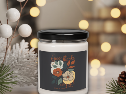 Candle jar with 'Give Thanks' label surrounded by decorative elements on a blurred background