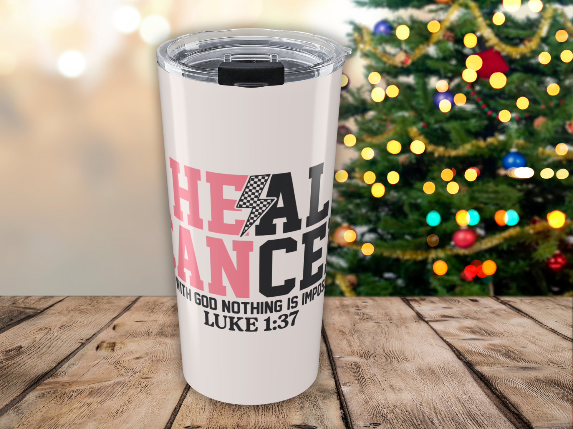 Pink tumbler with motivational quote in front of a decorated Christmas tree