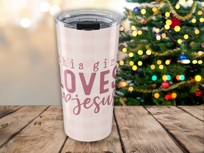 Tumbler with 'This girl loves Jesus' text in front of a decorated Christmas tree.