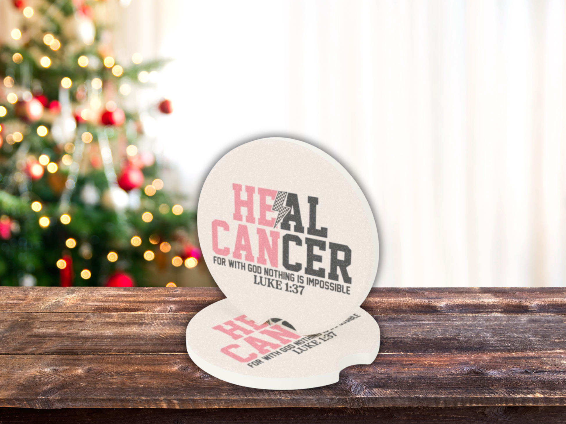 Decorative car coasters with 'Heal Cancer' text on a wooden surface with a Christmas tree in the background
