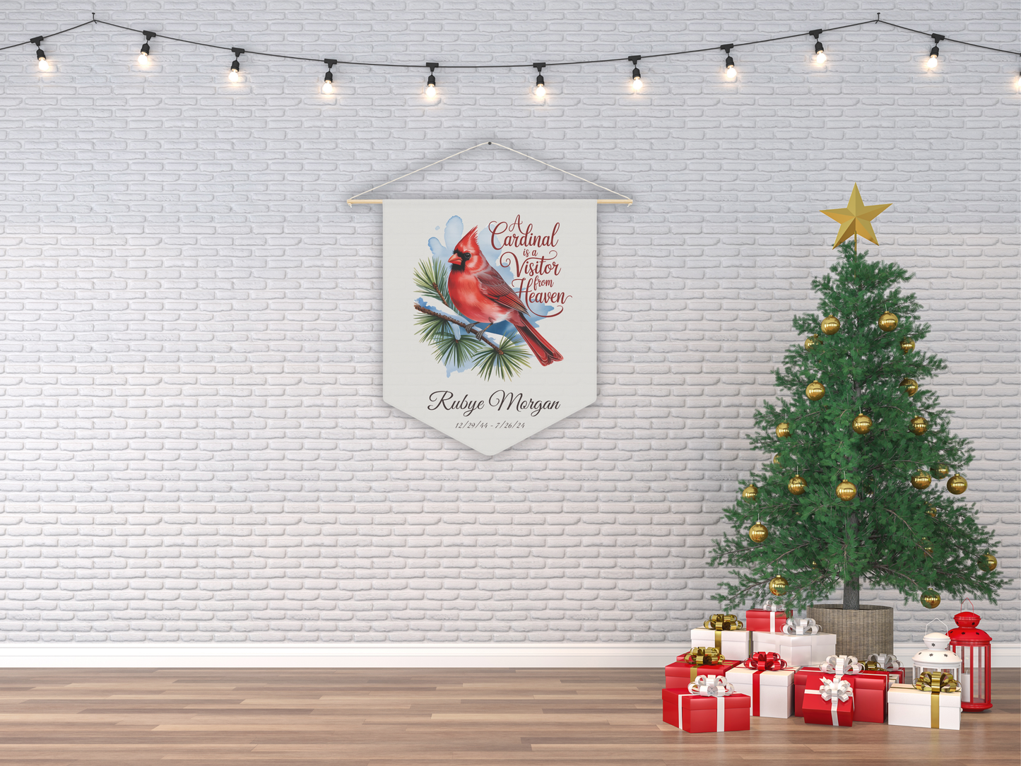 Decorative banner with a cardinal design hanging on a brick wall next to a Christmas tree and presents.