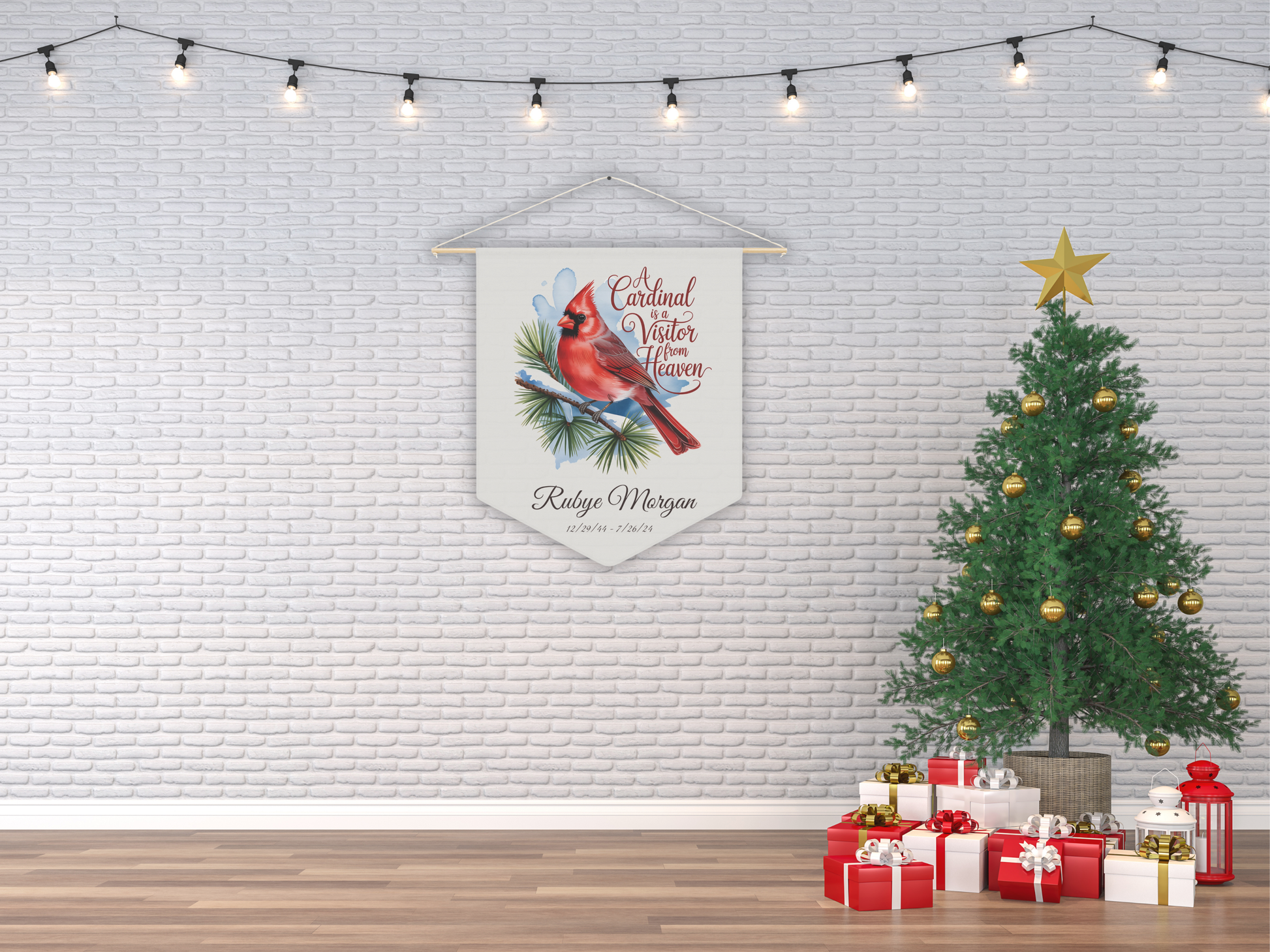 Decorative banner with a cardinal design hanging on a brick wall next to a Christmas tree and presents.