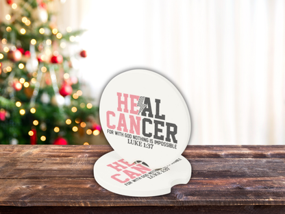 Decorative car coasters with 'Heal Cancer' text on a wooden surface with a Christmas tree in the background