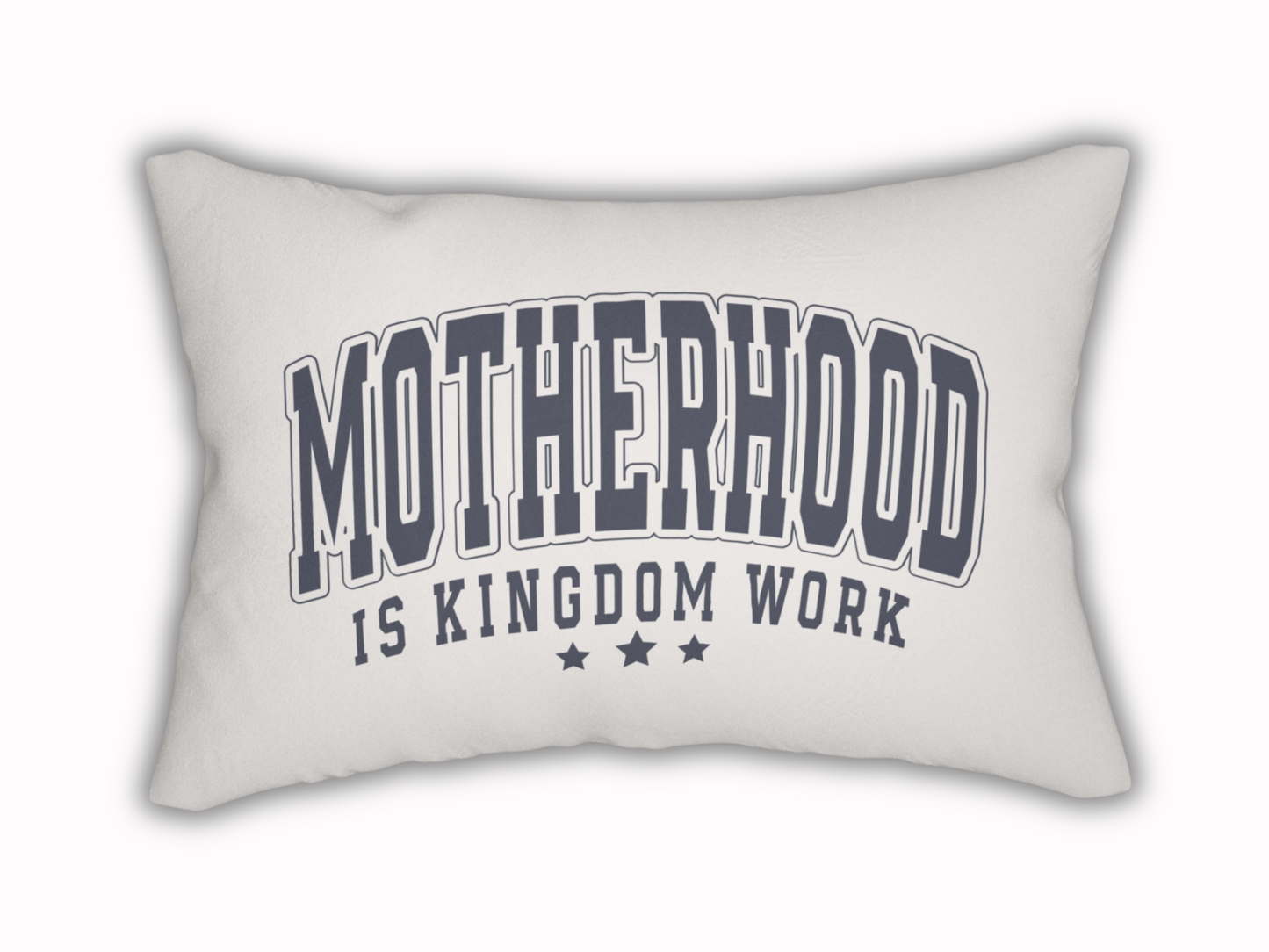 White rectangular pillow with bold navy text reading “Motherhood is Kingdom Work” and three stars beneath.