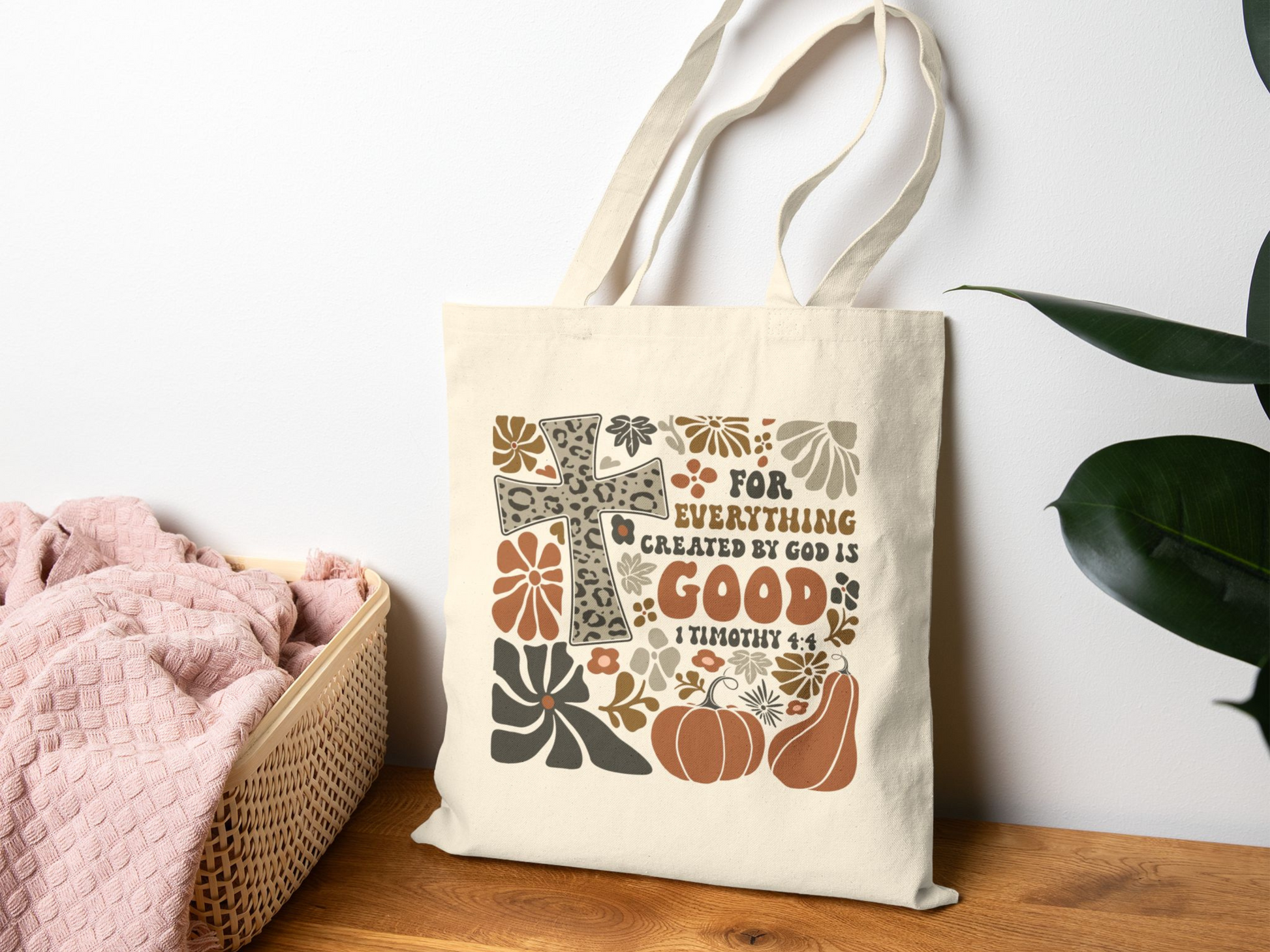 Tote bag with decorative design and text on a wooden surface with a plant in the background