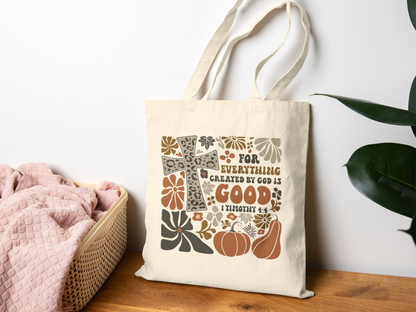 Tote bag with decorative design and text on a wooden surface with a plant in the background