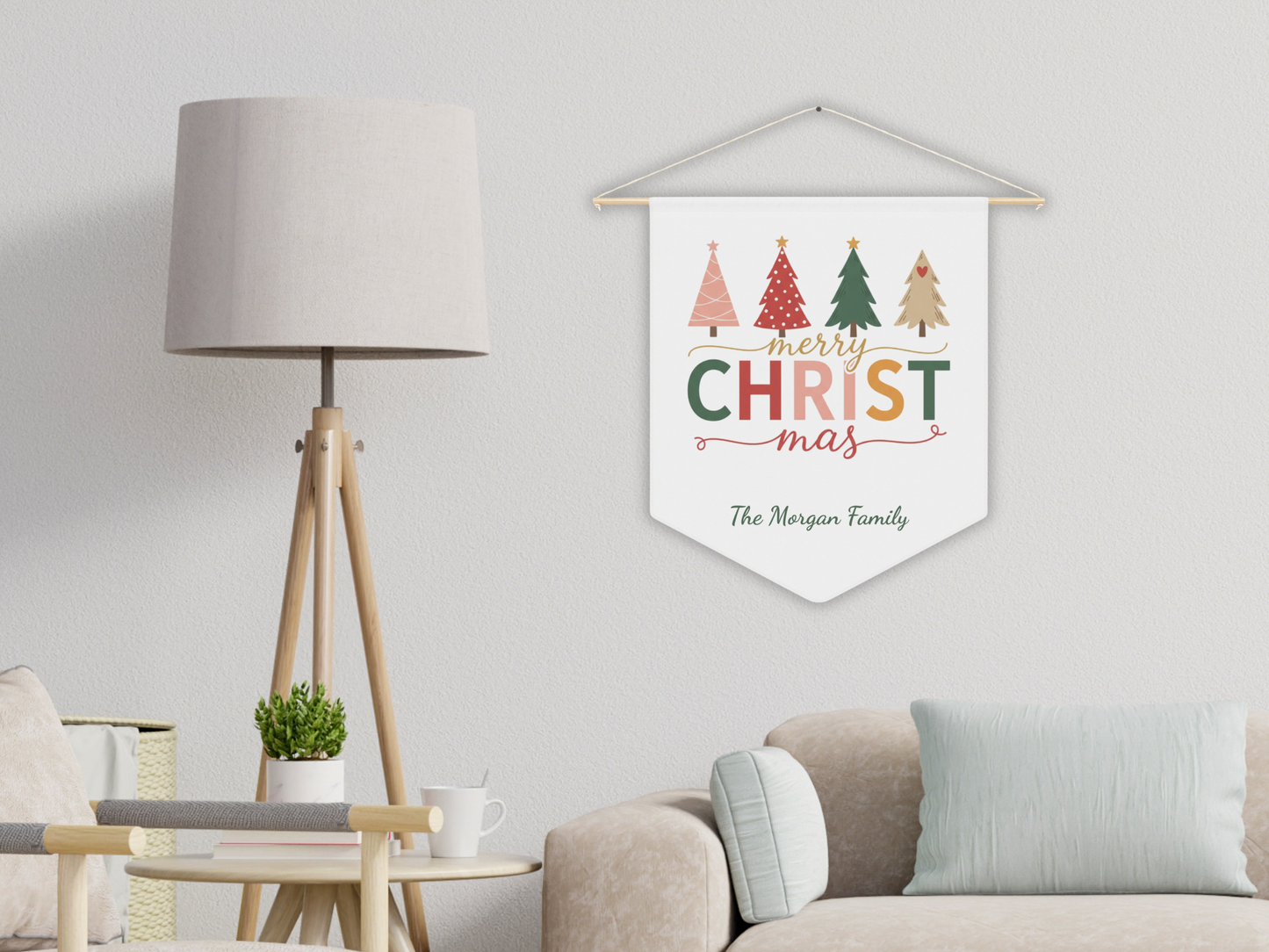 Decorative Christmas pennant with colorful trees and text hanging on a wall in a living room.