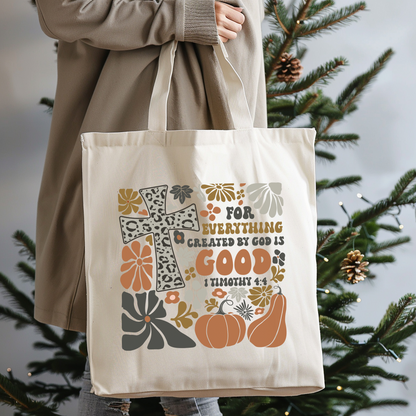 Tote bag with decorative design and text held by a person in front of a Christmas tree.