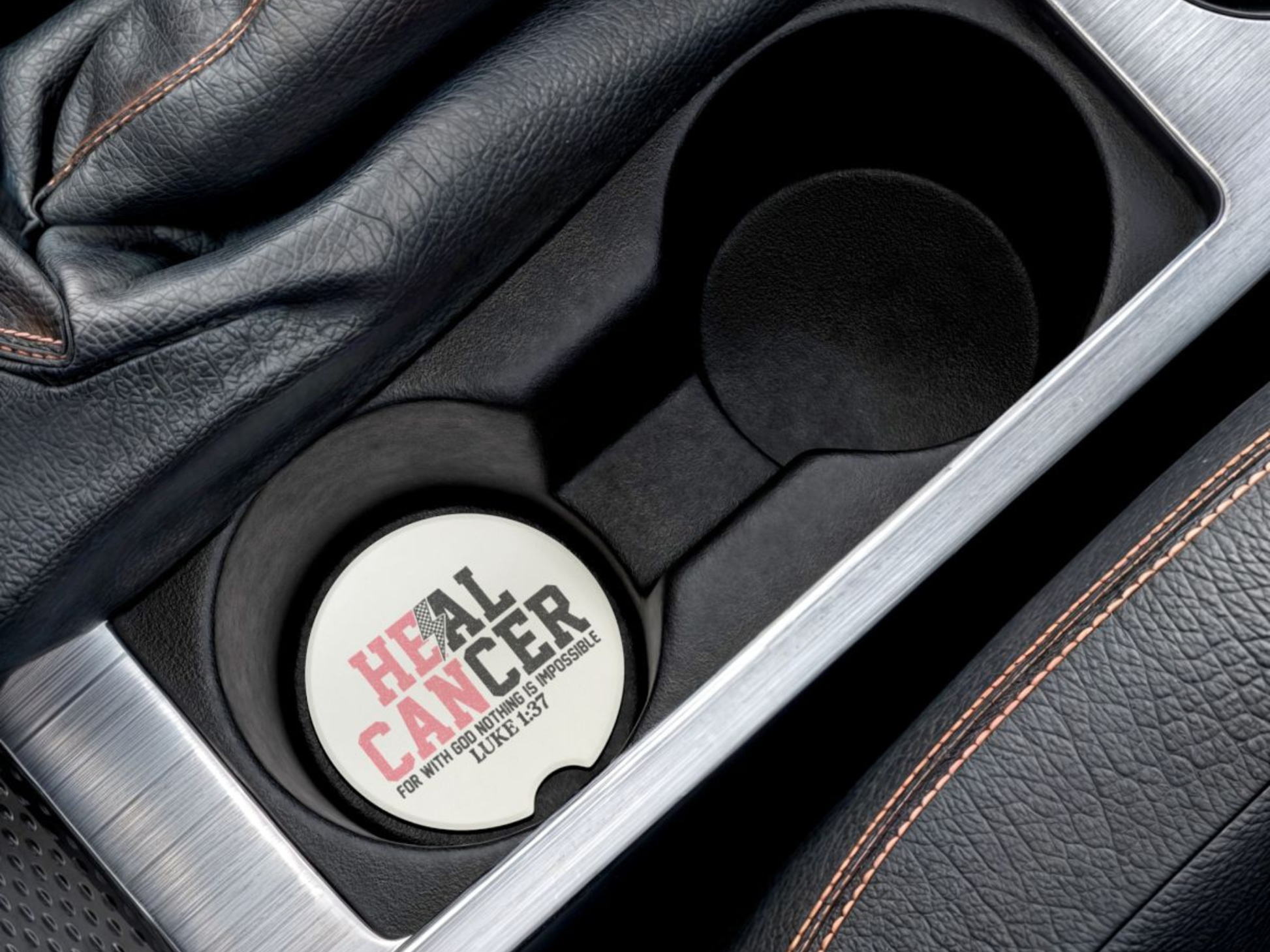Car cup holder with a circular coaster labeled 'HEAL CANCER' on a black leather interior.