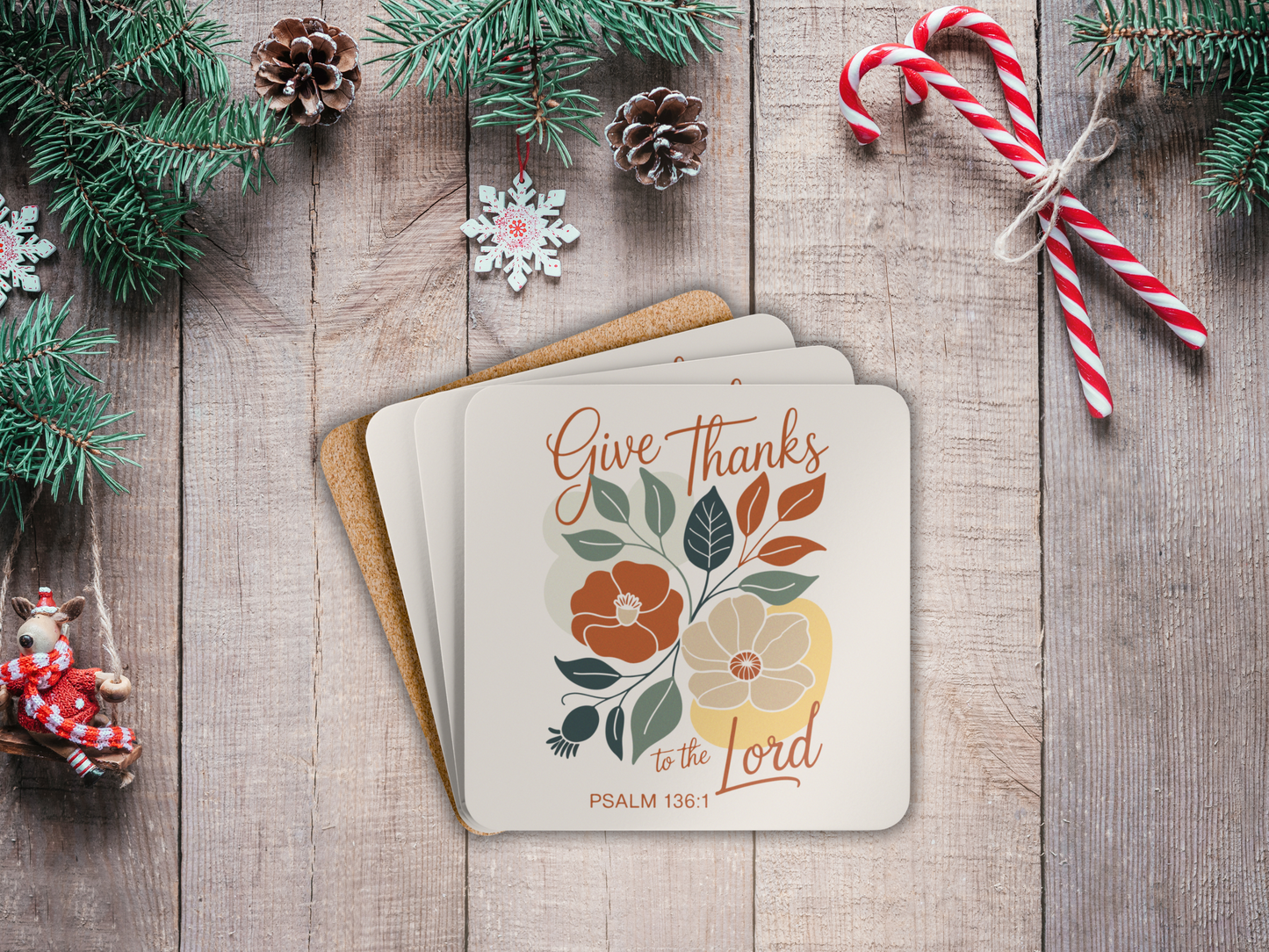Stack of coasters with floral design and text on a wooden surface with Christmas decorations.