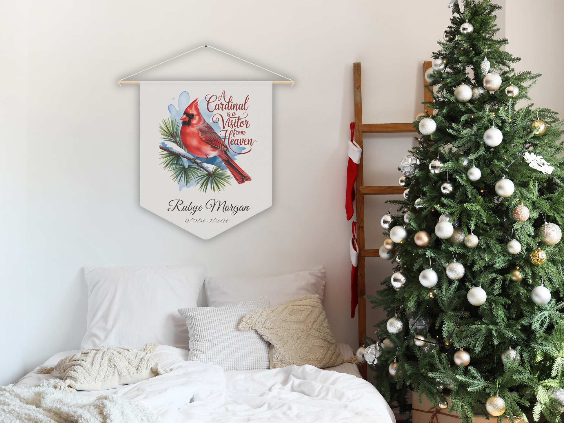 Decorative sign with cardinal and winter theme hanging above a bed next to a Christmas tree.