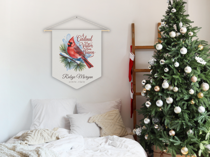 Decorative sign with cardinal and winter theme hanging above a bed next to a Christmas tree.