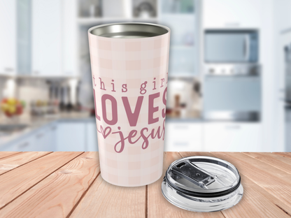 Pink tumbler with 'This girl loves Jesus' text on a wooden surface in a kitchen setting