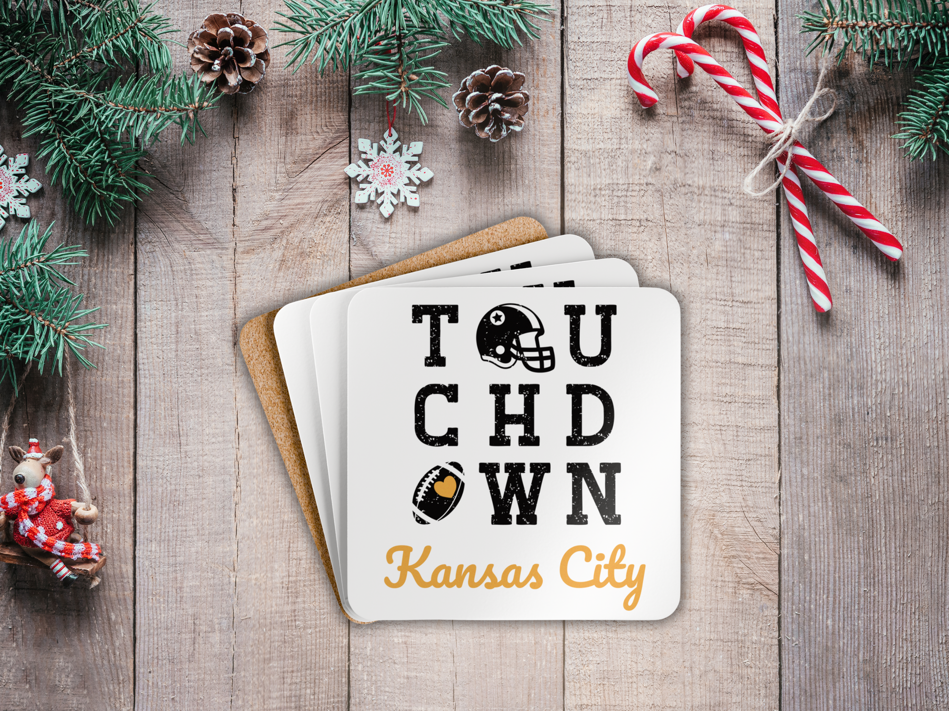 Stack of coasters with 'Touchdown Kansas City' text on a wooden surface with Christmas decorations.