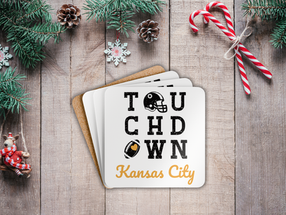 Stack of coasters with 'Touchdown Kansas City' text on a wooden surface with Christmas decorations.